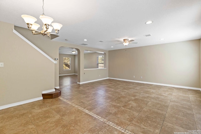 spare room featuring ceiling fan with notable chandelier