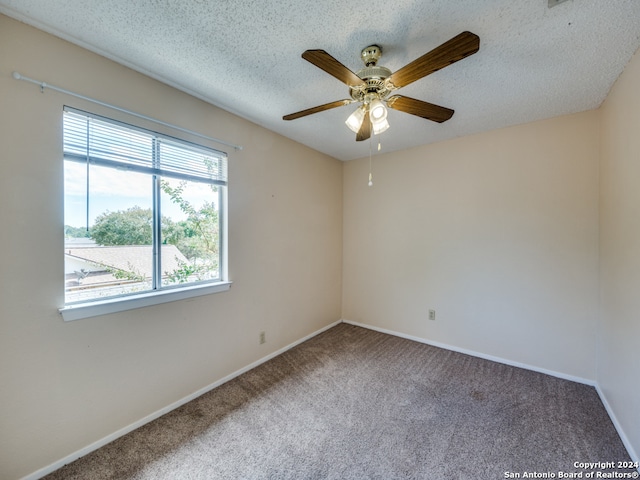 carpeted spare room featuring ceiling fan and a textured ceiling