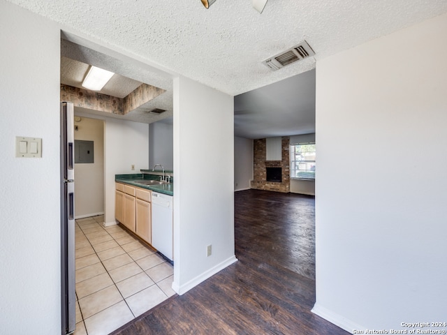 kitchen with a textured ceiling, sink, light wood-type flooring, and white dishwasher