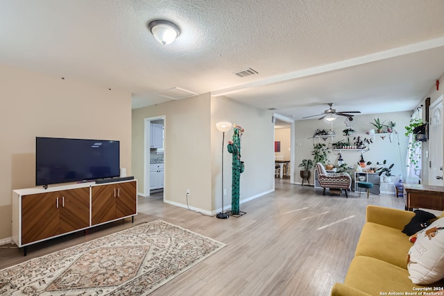 living room with ceiling fan, wood-type flooring, and a textured ceiling