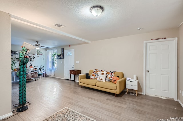 living room featuring a textured ceiling, wood-type flooring, and ceiling fan