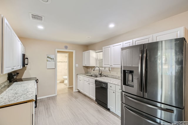 kitchen with white cabinets, light stone counters, appliances with stainless steel finishes, light hardwood / wood-style flooring, and sink