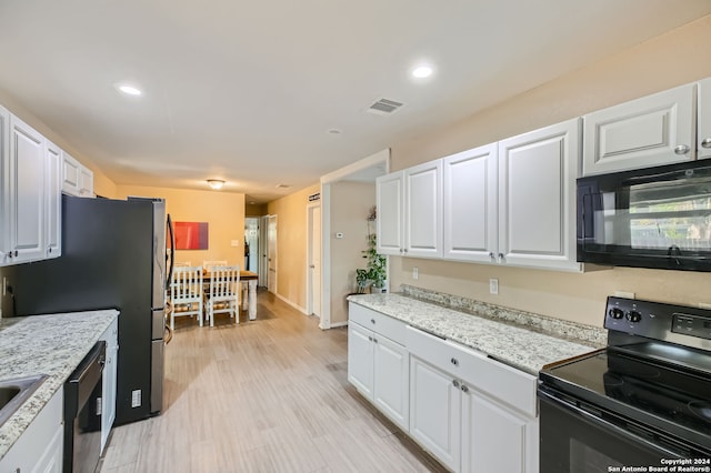 kitchen featuring white cabinetry, light stone countertops, black appliances, and light wood-type flooring