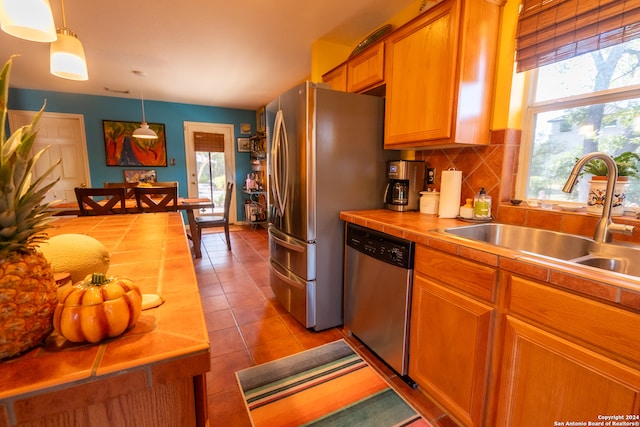 kitchen with pendant lighting, stainless steel appliances, plenty of natural light, and tasteful backsplash