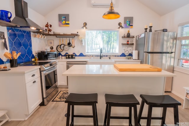 kitchen with white cabinetry, exhaust hood, appliances with stainless steel finishes, light wood-type flooring, and vaulted ceiling