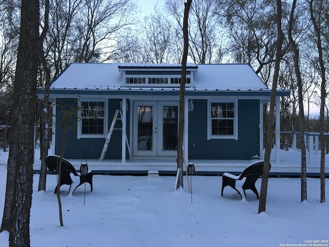 snow covered rear of property with covered porch