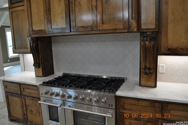 kitchen featuring stainless steel range, light stone countertops, and light hardwood / wood-style flooring