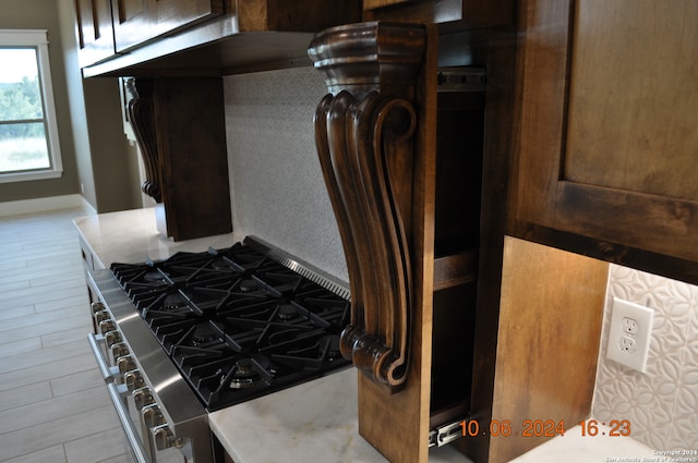 interior details with dark brown cabinetry, high end stainless steel range oven, and light wood-type flooring