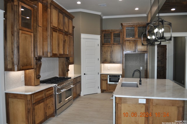 kitchen with light wood-type flooring, a notable chandelier, sink, stainless steel appliances, and backsplash