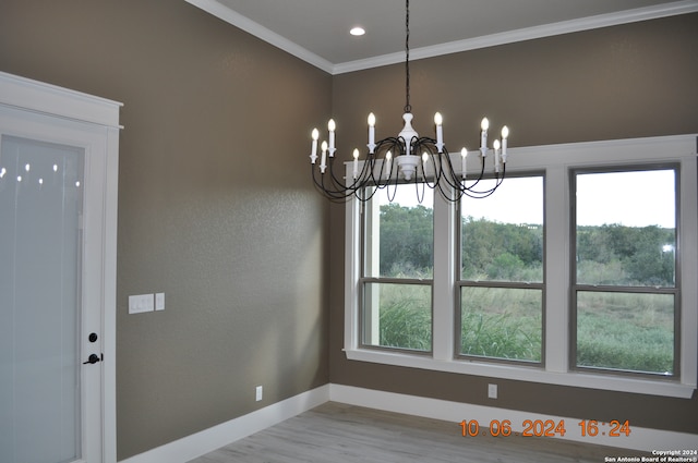 unfurnished dining area with a notable chandelier, crown molding, and light hardwood / wood-style floors