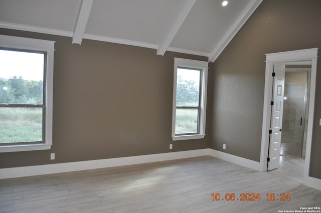 spare room featuring light hardwood / wood-style floors, crown molding, and lofted ceiling with beams