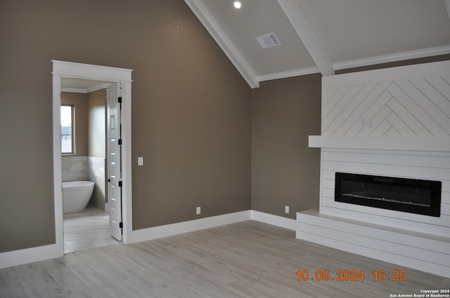 unfurnished living room featuring a fireplace, crown molding, lofted ceiling with beams, and light wood-type flooring