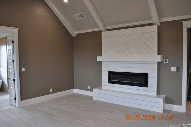 unfurnished living room featuring ornamental molding, lofted ceiling with beams, and light hardwood / wood-style floors