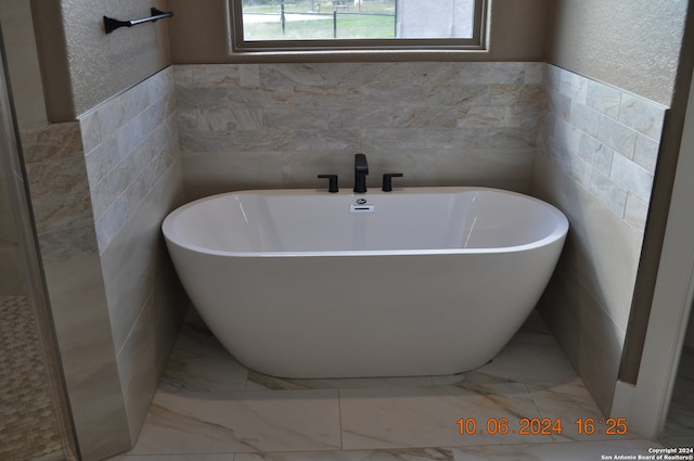 bathroom featuring tile walls and a tub