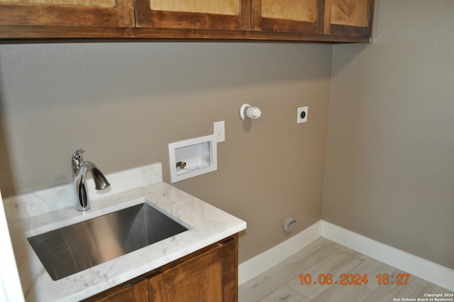 laundry area with hookup for a washing machine, hookup for an electric dryer, sink, cabinets, and light hardwood / wood-style flooring