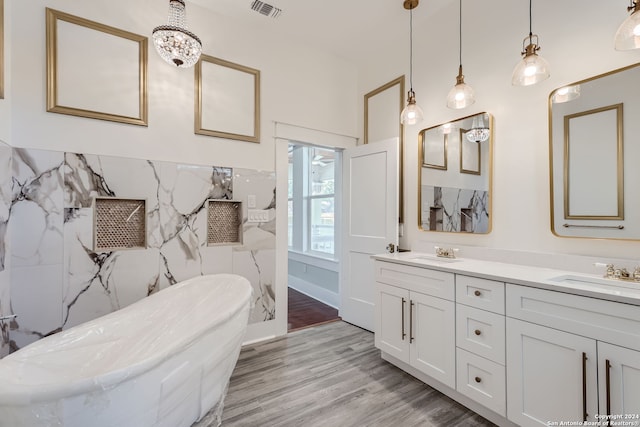 bathroom with tile walls, vanity, hardwood / wood-style flooring, and a bathing tub