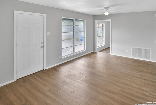 empty room featuring a textured ceiling, light hardwood / wood-style floors, and ceiling fan