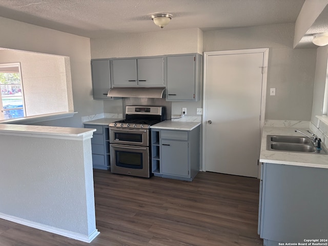 kitchen with sink, a textured ceiling, dark hardwood / wood-style flooring, gray cabinets, and double oven range