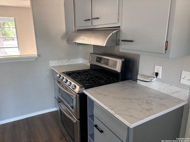 kitchen with stainless steel range with gas cooktop, dark wood-type flooring, gray cabinetry, and extractor fan