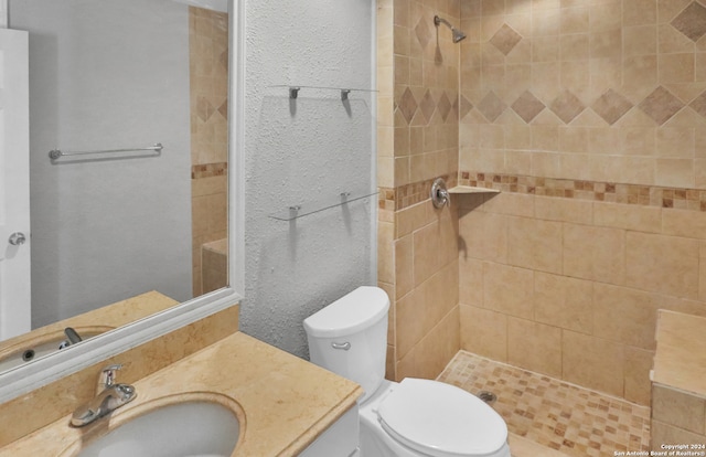 bathroom with vanity, toilet, and tiled shower