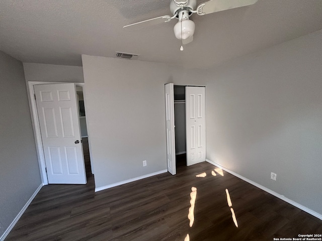 unfurnished bedroom featuring a closet, dark hardwood / wood-style floors, a textured ceiling, and ceiling fan