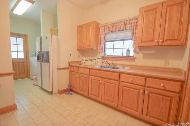 kitchen with a wealth of natural light, sink, white refrigerator with ice dispenser, and light tile patterned flooring