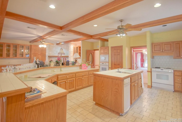 kitchen with beam ceiling, white appliances, a large island, tile counters, and light brown cabinetry