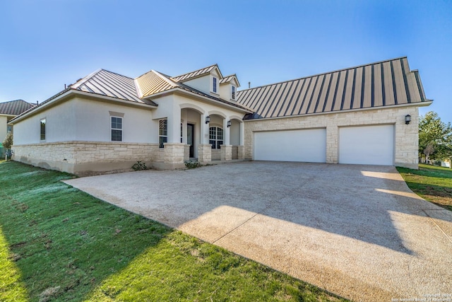 view of front of home featuring a standing seam roof, metal roof, stone siding, an attached garage, and concrete driveway