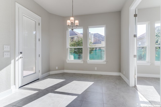 unfurnished dining area featuring tile patterned floors, a wealth of natural light, and a chandelier