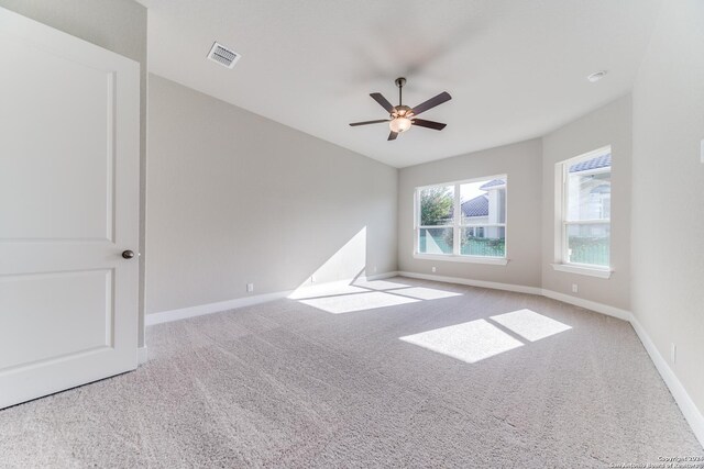 carpeted spare room featuring baseboards, a ceiling fan, and visible vents