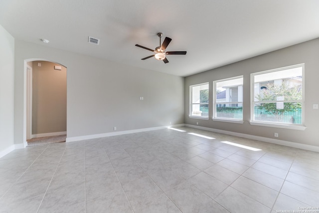 unfurnished room featuring arched walkways, ceiling fan, visible vents, and light tile patterned floors