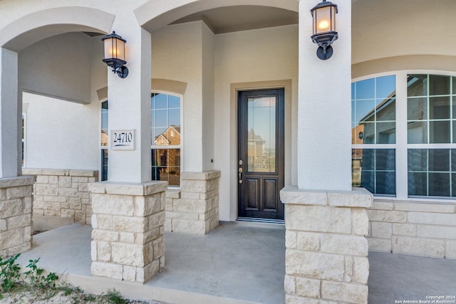 view of exterior entry featuring stucco siding and stone siding