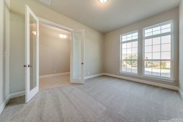 carpeted spare room with a healthy amount of sunlight and french doors