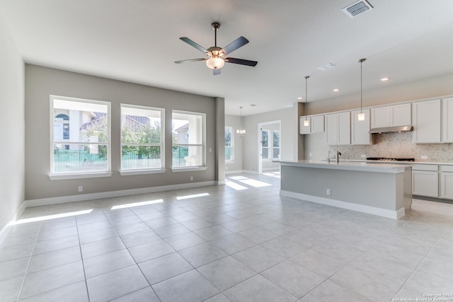 kitchen with open floor plan, decorative backsplash, visible vents, and under cabinet range hood