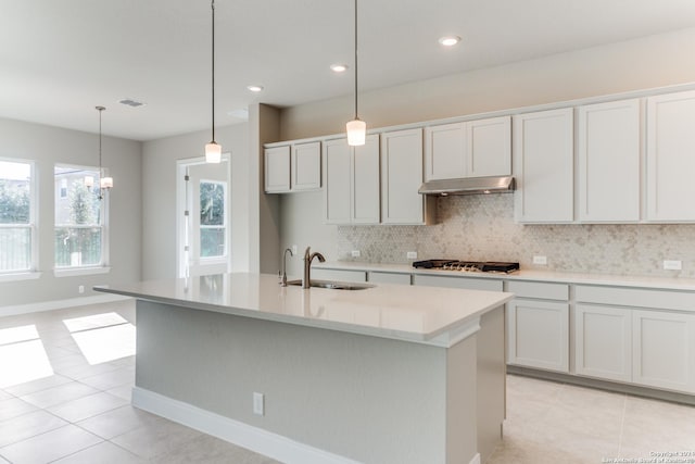 kitchen with light tile patterned flooring, under cabinet range hood, visible vents, stainless steel gas cooktop, and decorative backsplash