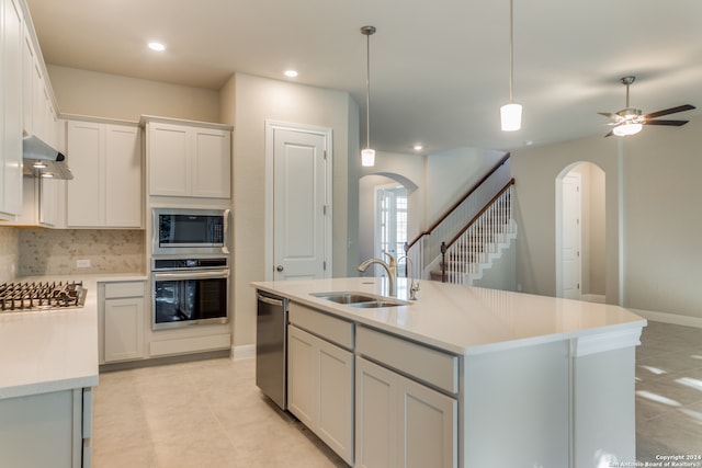 kitchen featuring white cabinets, an island with sink, sink, decorative light fixtures, and backsplash