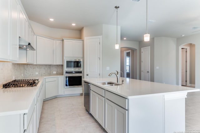 kitchen featuring arched walkways, a sink, wall chimney range hood, and stainless steel appliances
