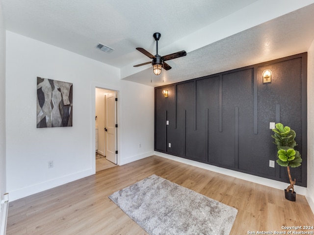 bedroom featuring light hardwood / wood-style floors, ensuite bathroom, a textured ceiling, and ceiling fan