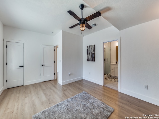 unfurnished bedroom with light hardwood / wood-style floors, connected bathroom, a textured ceiling, and ceiling fan