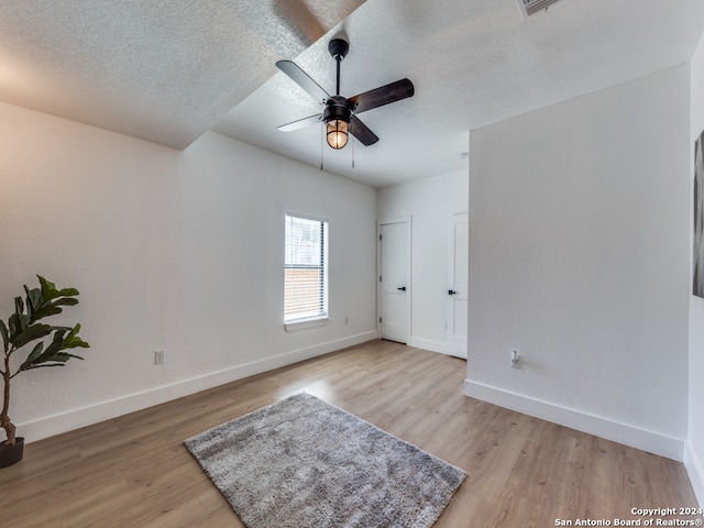 empty room with light wood-type flooring, ceiling fan, and a textured ceiling