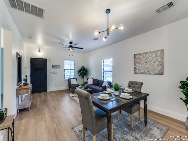 dining space featuring ceiling fan with notable chandelier and light hardwood / wood-style floors