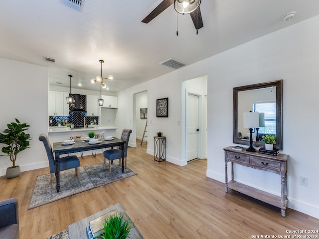 dining area with ceiling fan with notable chandelier and light wood-type flooring