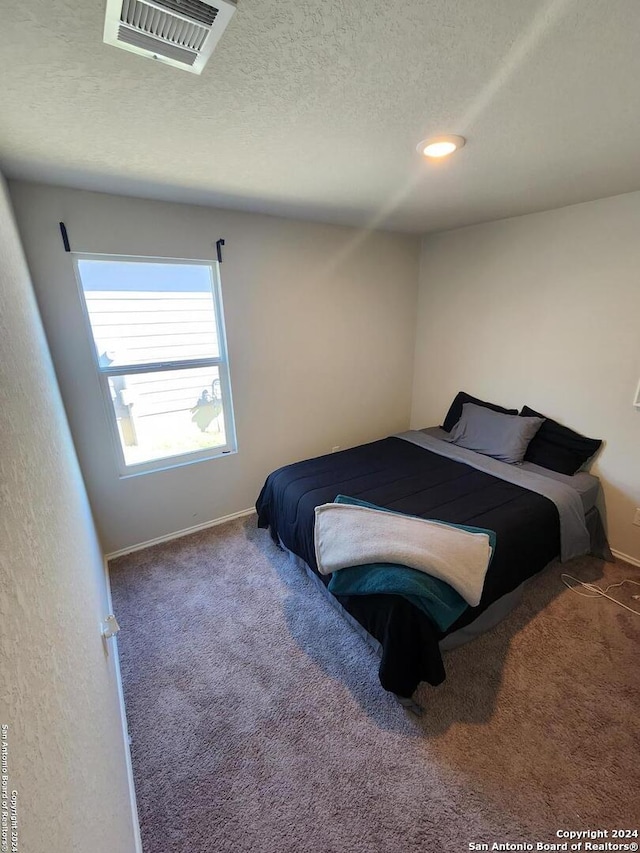 bedroom featuring dark colored carpet and a textured ceiling