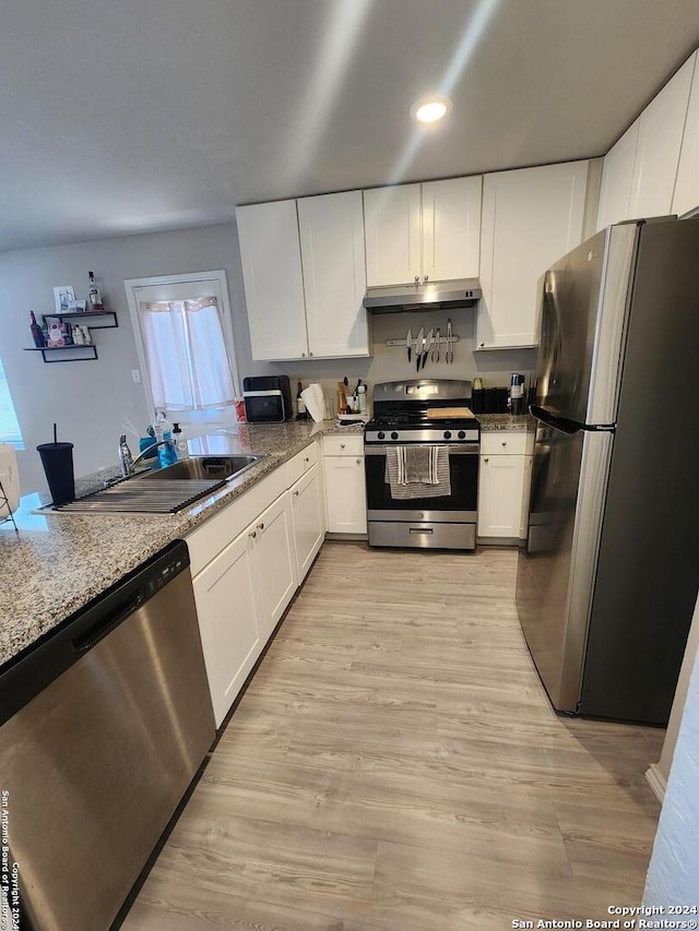 kitchen featuring sink, stone countertops, white cabinetry, stainless steel appliances, and light hardwood / wood-style floors