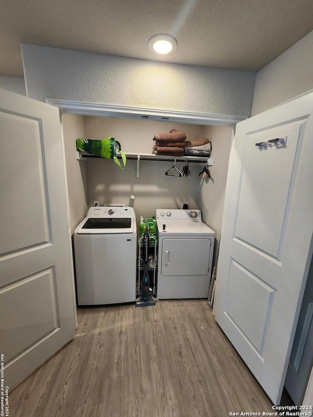 clothes washing area with light hardwood / wood-style flooring, a textured ceiling, and washer and clothes dryer