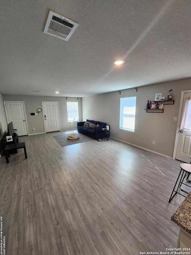 unfurnished living room featuring hardwood / wood-style flooring and a textured ceiling