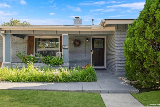 entrance to property with a yard and covered porch