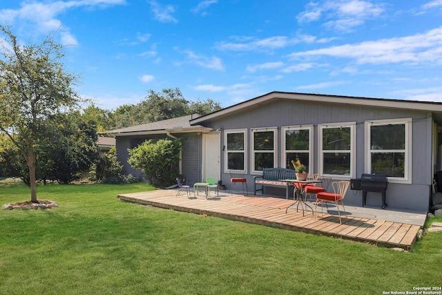 rear view of house with a wooden deck and a lawn