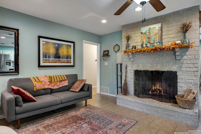 living room featuring a brick fireplace, tile patterned floors, and ceiling fan