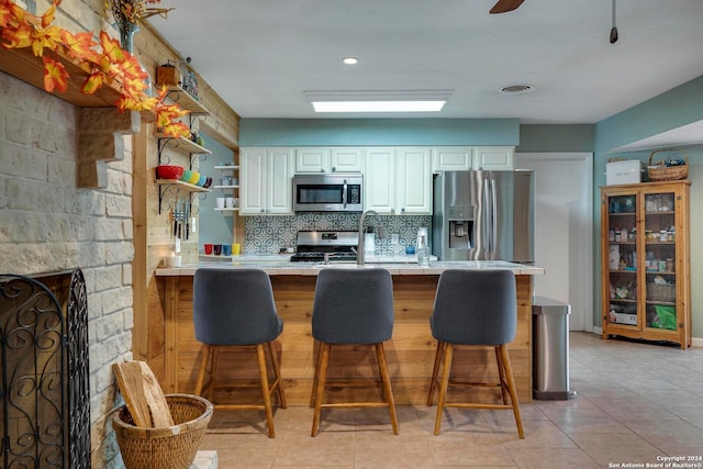 kitchen featuring white cabinets, stainless steel appliances, a fireplace, and a breakfast bar